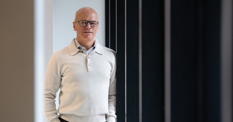 Prof Bobby McFarland in a white jumper, leaning against a wall